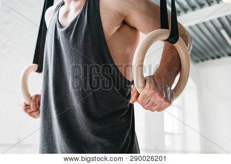 Male Gymnast Doing Workout On Gymnastics Rings In Cross Gym. Fit Athlete Exercises On Crosstraining 