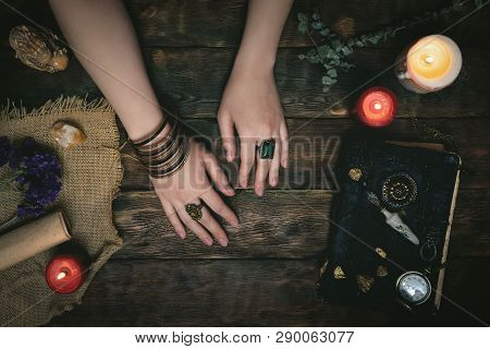 Enchantress Female Hands And An Ancient Magic Book In The Light Of Burning Candle On A Wooden Table 