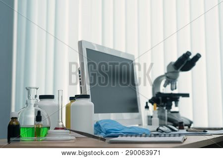 Laboratory Table With Microscope, Flasks And A Desktop Computer Above On A Window Light Background. 