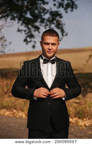 Young Man Walking In The Park. Handsome Groom In Black Suit
