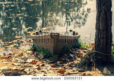 A Half Sunken Boat In A Lake In The Afternoon Sunshine.