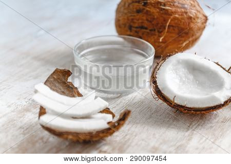 Whole Coconut Cut Into Chunks And Chips And Milk On A Light White Wooden Background. Top View.