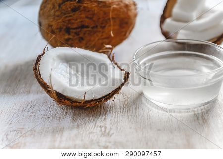 Whole Coconut Cut Into Chunks And Chips And Milk On A Light White Wooden Background. Top View.