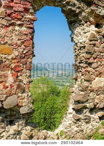 Round Hole In Destroyed Defensive Wall Of The Medieval Fortress, Through Which You Can See Mountain 