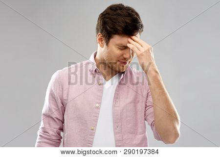 mind, health problem and stress concept - unhappy indian man suffering from headache over grey background