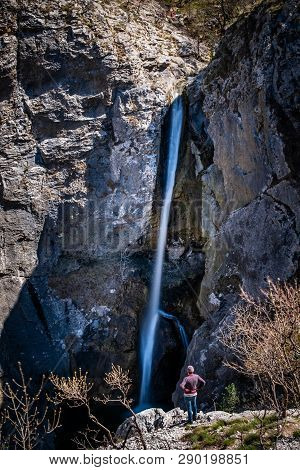 Man Standing Near Very High Waterfall In Natural Park Rosandra Near Triest In Italy, Europe