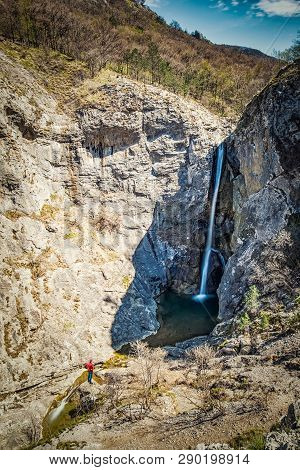 Man Standing Near Very High Waterfall In Natural Park Rosandra Near Triest In Italy, Europe