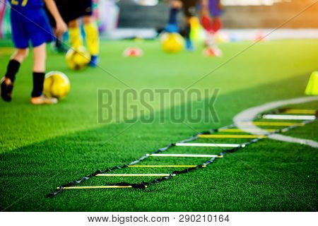 Selective Focus To Ladder Drills On Green Artificial Turf With Blurry Coach And Kid Soccer Are Train