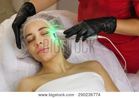 Hardware Cosmetology. Ultrasound Chromotherapy. Beautician Carries Out Procedure For Tightening Skin
