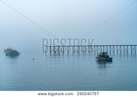 Fishing Boats At Anchor In Harbor And Mist At Moeraki In South Island.