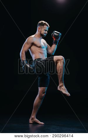 Muscular Barefoot Strenuous Boxer In Boxing Gloves Doing Kick On Black