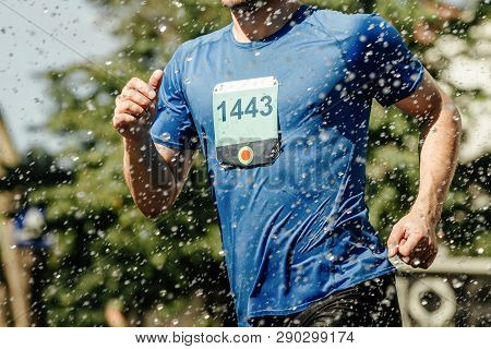 Male Runner Running Marathon In City In Foreground Splashing Water