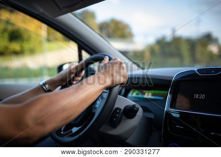 Young man driving an electric vehicle in a city context. Car sharing concept. eCar concept.