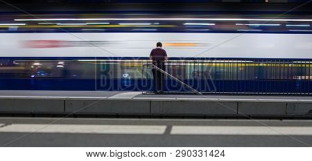 People in a trainstation with motion blurred trains moving fast (color toned image)
