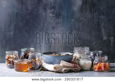 Variety Of Dried Fruits, Nuts, Honey And Oat Flakes In Bowl And Different Glass Jars For Cooking Hom