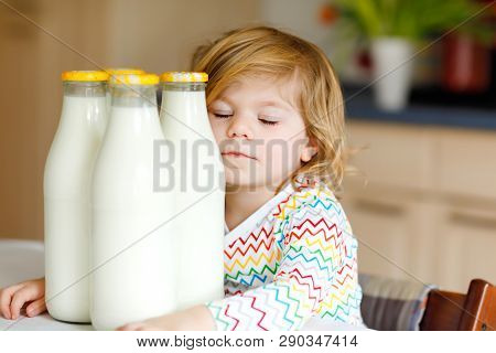 Adorable Toddler Girl Drinking Cow Milk For Breakfast. Cute Baby Daughter With Lots Of Bottles. Heal