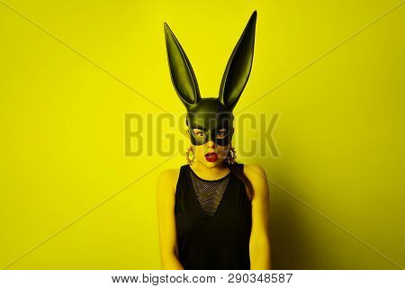 Sexy Young Woman With Red Lipstick And Large Breasts Wearing A Black Mask. Easter Bunny Standing On 