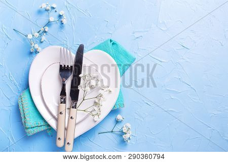 White Plates In Form Of Hearts, Napkin, Knife And Fork And  Fresh White Gypsofila  Flowers On Blue T