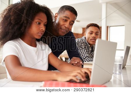 Middle aged black dad helping his teen kids with homework, low angle, close up