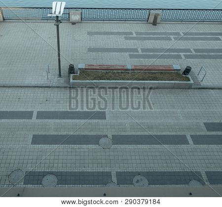 View From Top On Modern Empty Embankment With City Lantern, Bench And Lot Of Hatchways