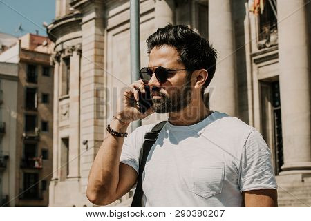 Handsome Bearded Hispanic Man Using Mobile Smartphone For Surfing Web Internet, Making Call And Look