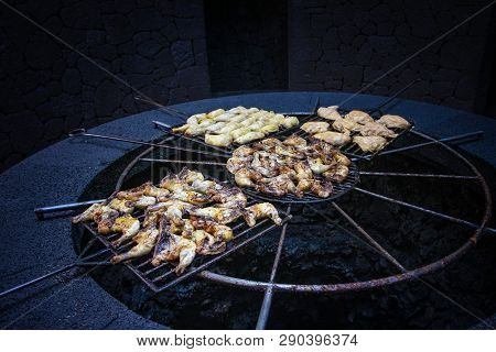 Chicken Pieces Are Baked And Roust On A Grill Above The Volcanic Stone.