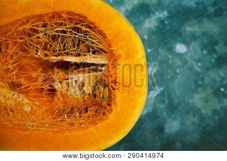 Part Of The Cut Pumpkin Is Orange On A Turquoise Background Close-up.