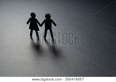 Paper figure of a couple holding hands on gray surface. Loneliness, childless, old age concept.