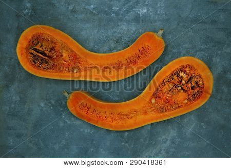 Two Halves Of A Pear-shaped Pumpkin Of Orange Color, Are Located Against Turquoise Color Horizontall