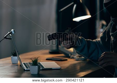 Cropped View Of Criminal In Mask Aiming Gun At Laptop Screen