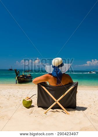 Woman with straw hat enjoying her holidays on a transat at the tropical beach in Thailand