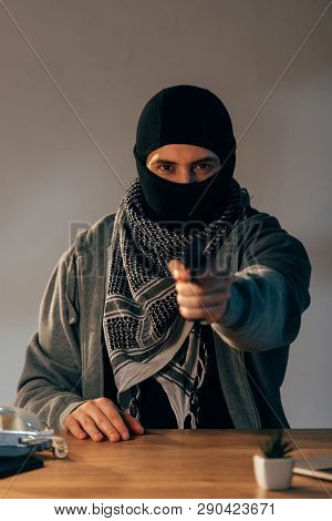 Concentrated Criminal In Black Mask Aiming Gun At Camera