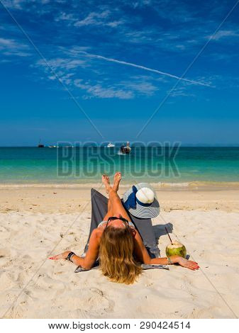 Woman with straw hat enjoying her holidays on a transat at the tropical beach in Thailand