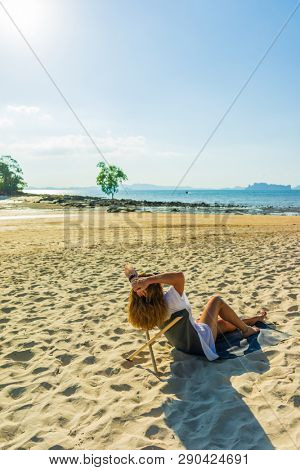 Woman enjoying her holidays on a transat at the tropical beach in Thailand