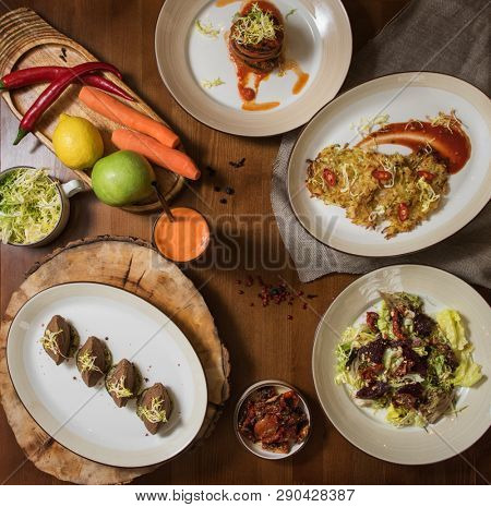 Healthy vegeterian food on brown wood board. Spring vitamin dieting food. Salad from beet with dried tomatoes and cabbage, potato vegan pancakes, dried tomatoes, pate from red beans, baked vegetables