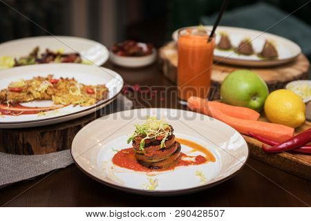 Healthy vegeterian food on brown wood board. Spring vitamin dieting food. Baked vegetables in layers, fruits and carrot juice