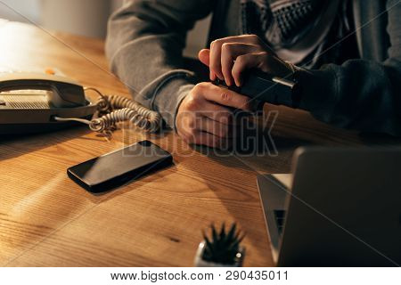 Partial View Of Criminal Sitting At Table And Holding Gun
