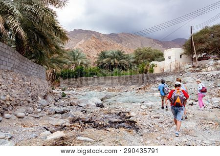 Muscat, Oman - December 16, 2018: Group Of Tourists Is Walking Along The Wadi - A Dried Up Riverbed 