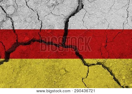 South Ossetia Flag On The Cracked Earth. National Flag Of South Ossetia. Earthquake Or Drought Conce