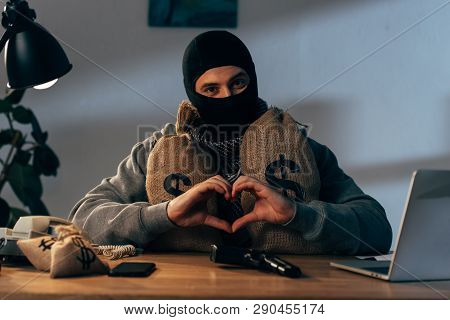 Terrorist In Mask With Money Bags Showing Heart Sign