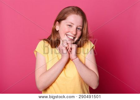 Beautiful Girl Stands Against Pink Wall, Dressed Casual Yellow T Shirt, Has Long Sraight Hair, Keeps