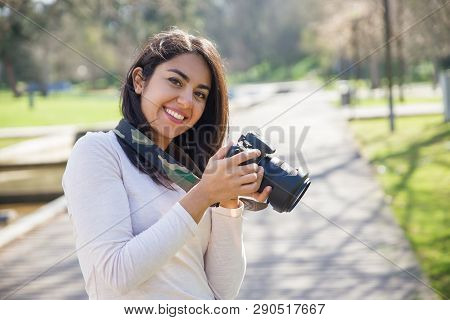 Positive Successful Photographer Enjoying Photo-shooting Outdoors. Young Woman In Casual Holding Pho