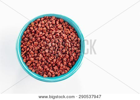Annatto Seeds In Blue Bowl, Isolated On White Background, Top View