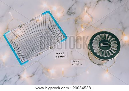 Spend Better For Less Waste Shopping Basket Next To Gargabe Bin And Fairy Lights On Marble Desk