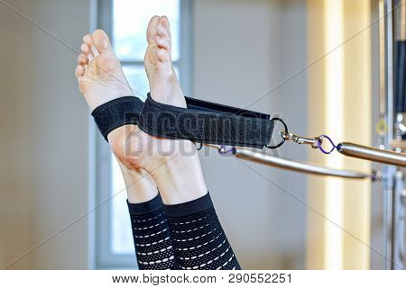 Gym Woman Pilates Stretching Sport In Reformer Bed Instructor Girl. Legs Close Up