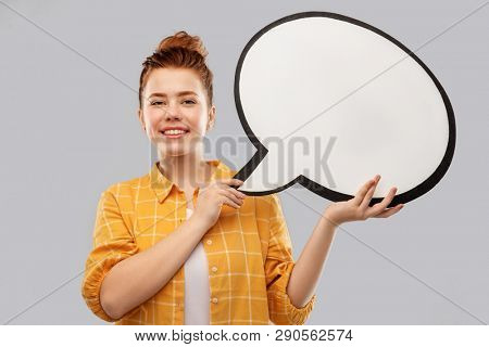 people concept - smiling red haired teenage girl in checkered shirt holding blank speech bubble over grey background