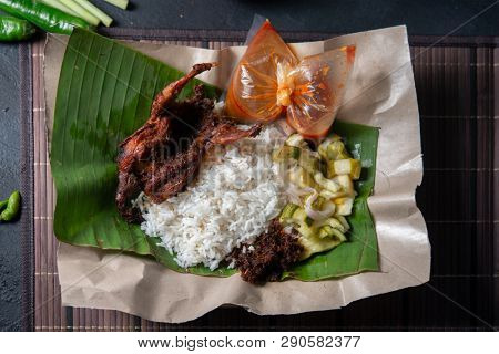 Nasi lemak kukus with quail, popular traditional Malay local food. Flat lay top down overhead view.