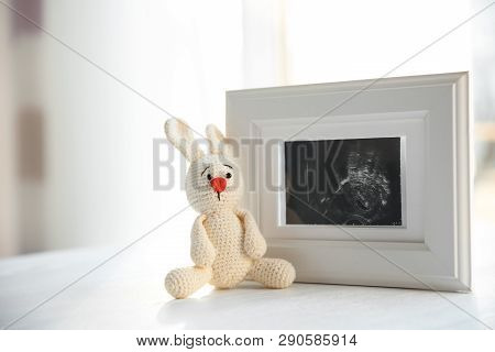 Ultrasound Photo Of Baby And Toy On Table Indoors, Space For Text