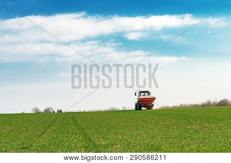 Unrecognizable Farmer In Agricultural Tractor Is Fertilizing Wheat Crop Field With Npk Fertilizer Nu