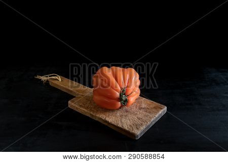 Colorful Juicy Ugly Tomato On Wooden Cutting Board On A Black Backgound, Rustic Style And Low Key